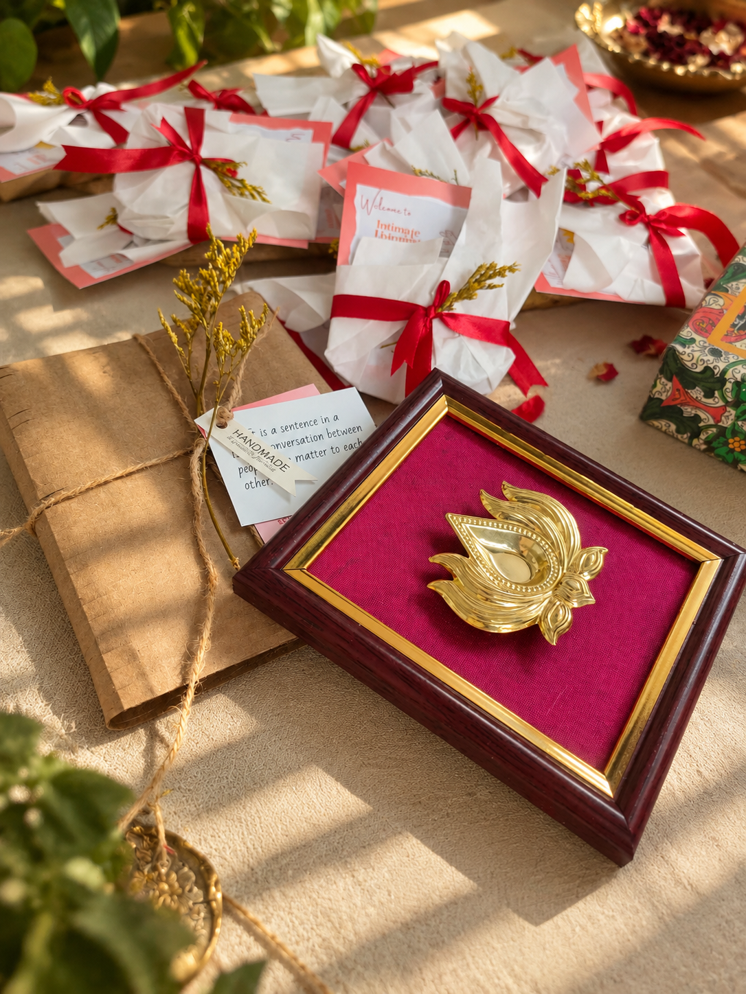 Handcrafted keepsake in a framed burgundy presentation surrounded by wrapped guest gifts with red ribbons